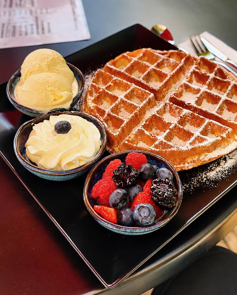 Frisch gebackene Waffel mit Vanilleeis, Sahne und frischen Beeren
