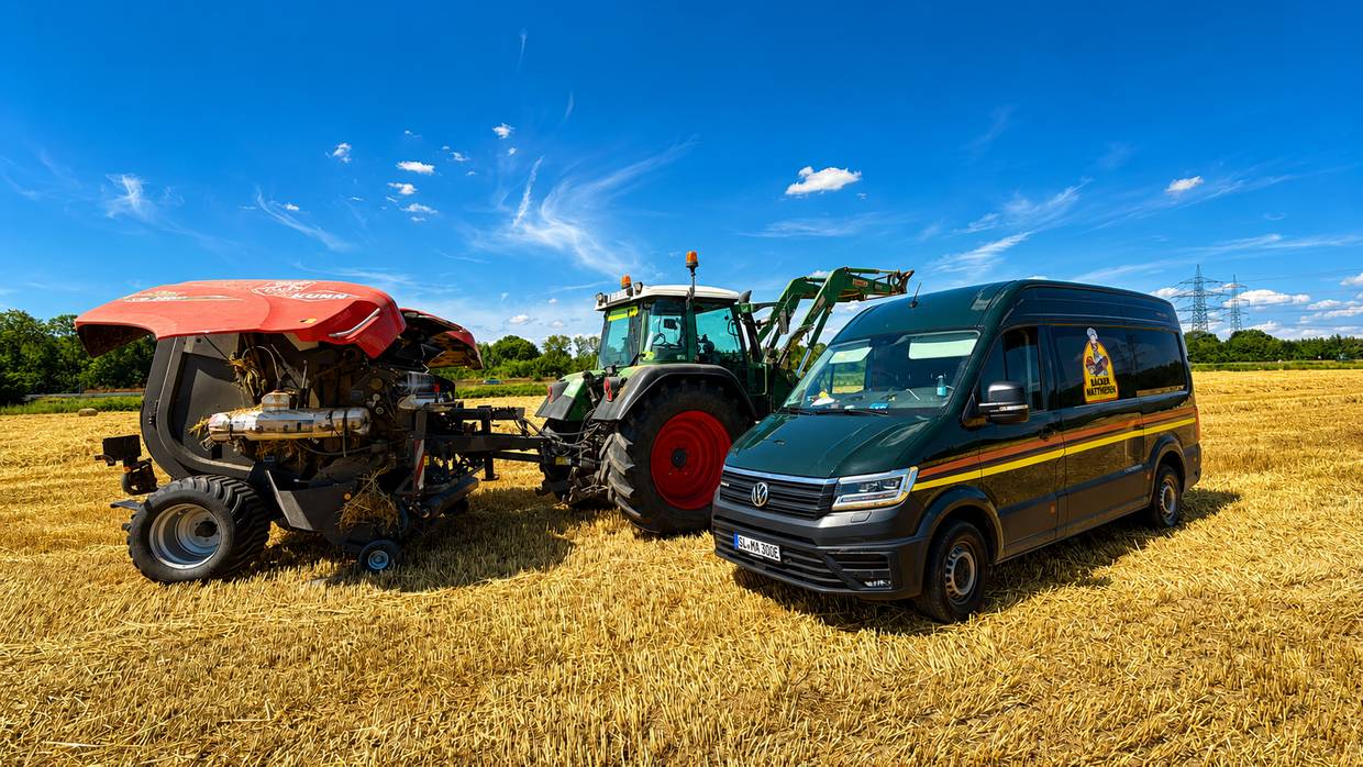 Ballenpresse und Traktor bei der Weizenernte – daneben der Lieferwagen von Bäcker Mattheisen